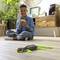 A boy sits smiling on the floor in a living room, playing with a toy dinosaur that has glowing parts.