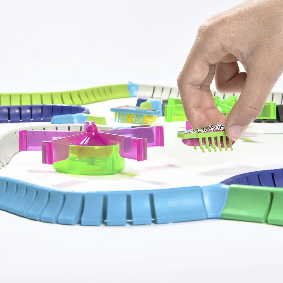 A table game where a hand is holding a printed card. Colourful, semi-circular playing fields are arranged around the game board.