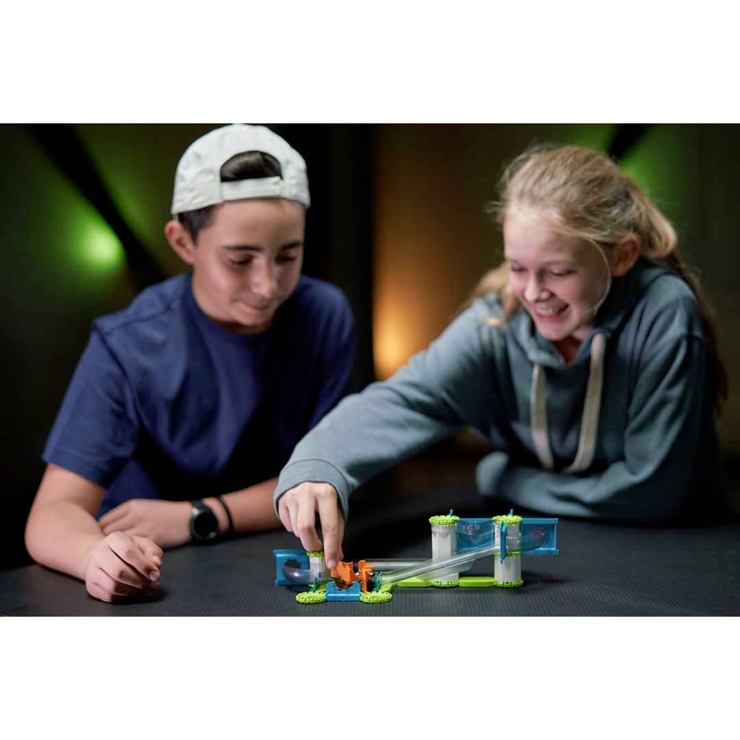 Two children are playing intently with a table toy consisting of colourful building blocks. They are indoors.