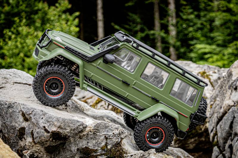 A green off-road vehicle model traverses steep rocks in the forest, demonstrating off-road capability and a spirit of adventure.