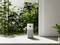 Air purifiers positioned in front of large windows overlooking lush green plants; modern, minimalist interior design.
