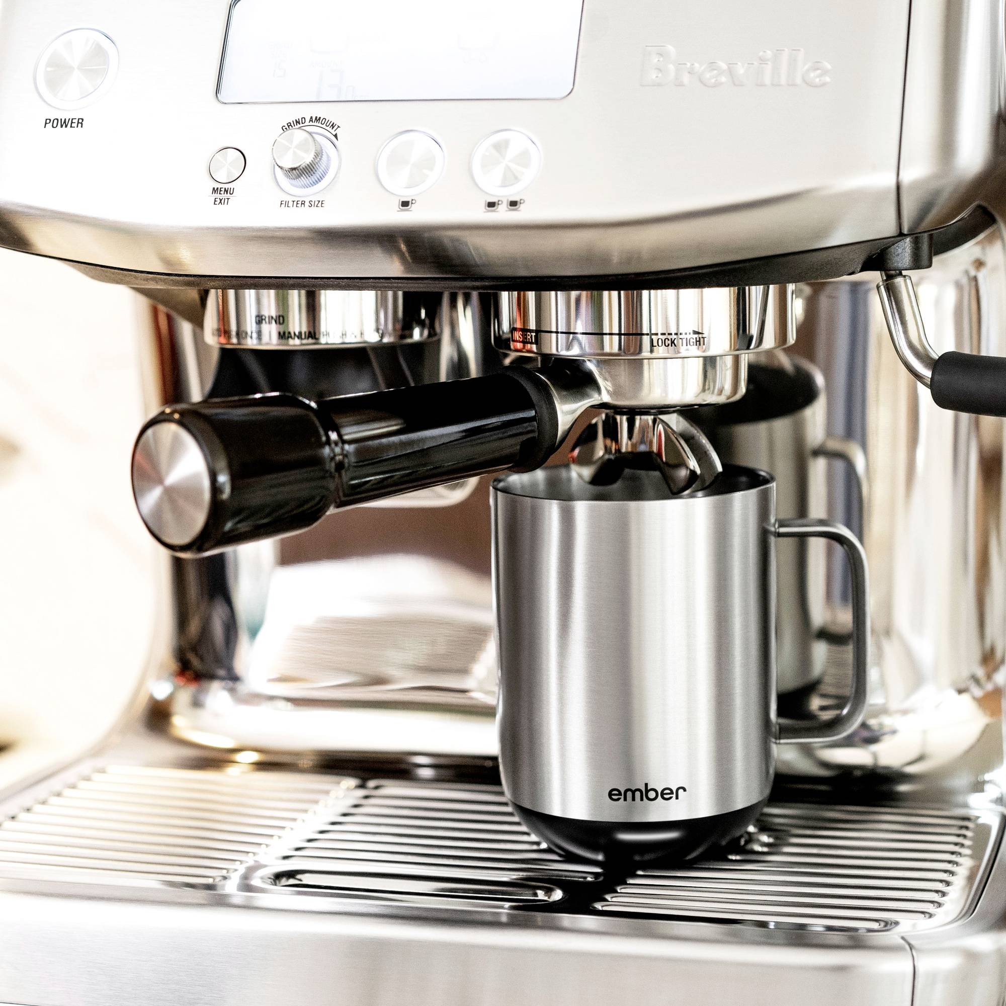A stainless steel espresso machine with an arm and a cup underneath.