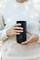 A person is holding a black thermal mug in both hands. Background blurred, focus on the mug.
