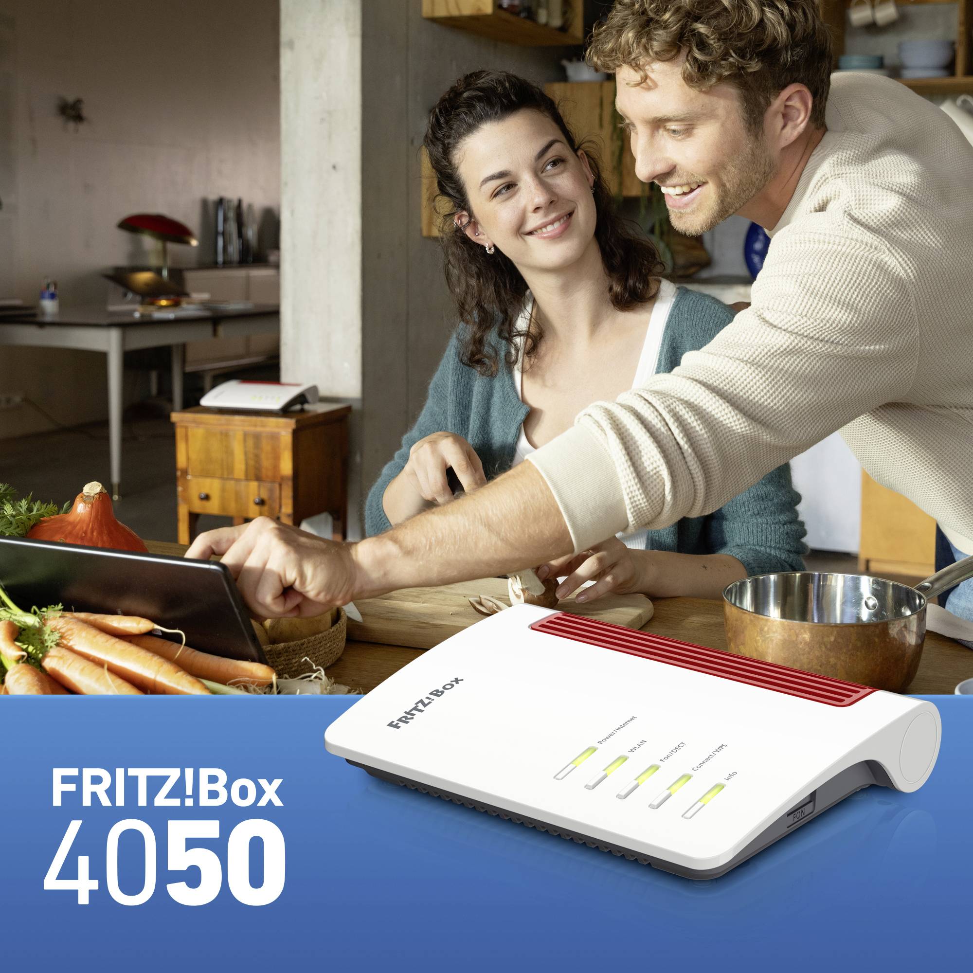 A smiling couple in a kitchen with a FRITZ!Box 4050 in the foreground. The FRITZ!Box has several illuminated indicators.