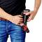 A person in jeans is holding a red and black cordless drill, ready for use. The focus is on the tool and how it is being held.