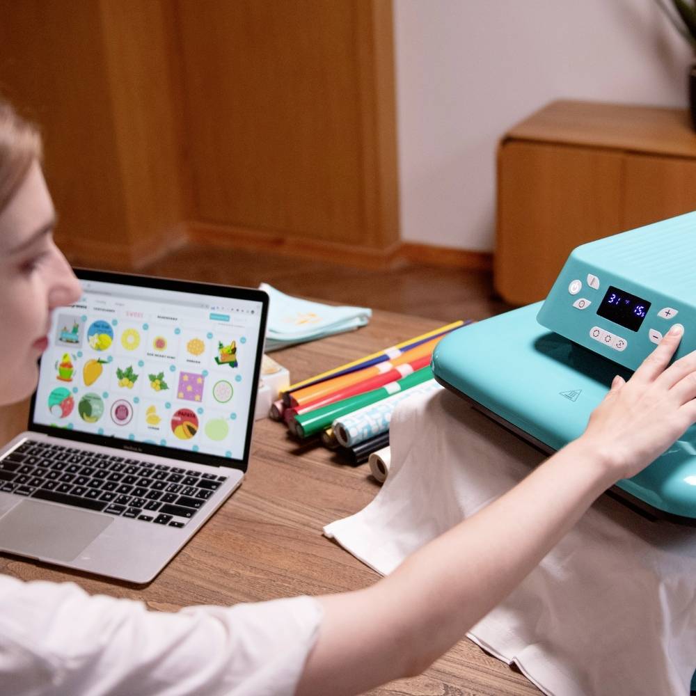 A person is working on a laptop with a colourful diagram. Next to them is a device with buttons and a display, showing 37.1 °C.