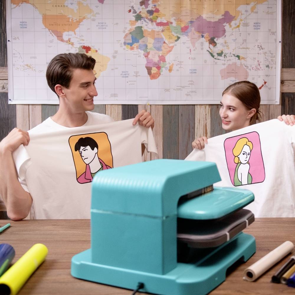 A man and a woman are presenting printed T-shirts with illustrations. A world map hangs on the wall in the background.