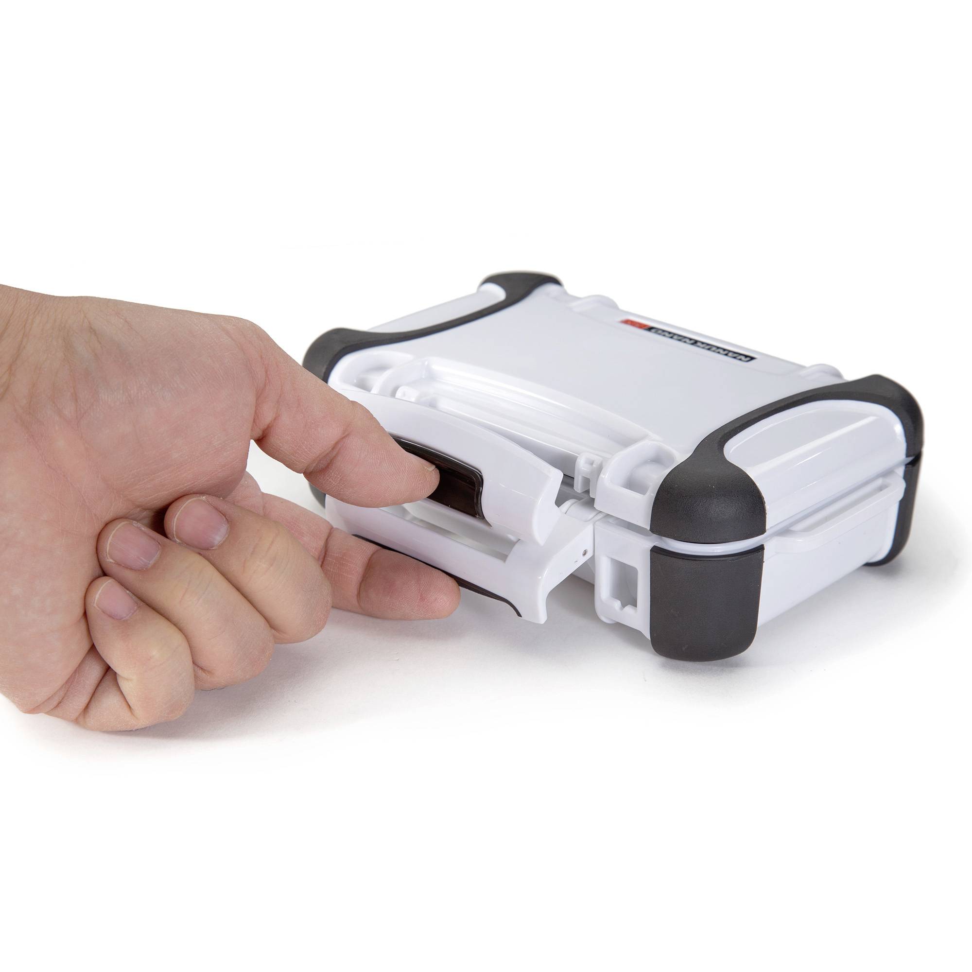 A person is pressing down on a small white suitcase with black corners and a clasp.