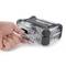 A hand is holding a compact, transparent suitcase with sturdy black corners and a handle.