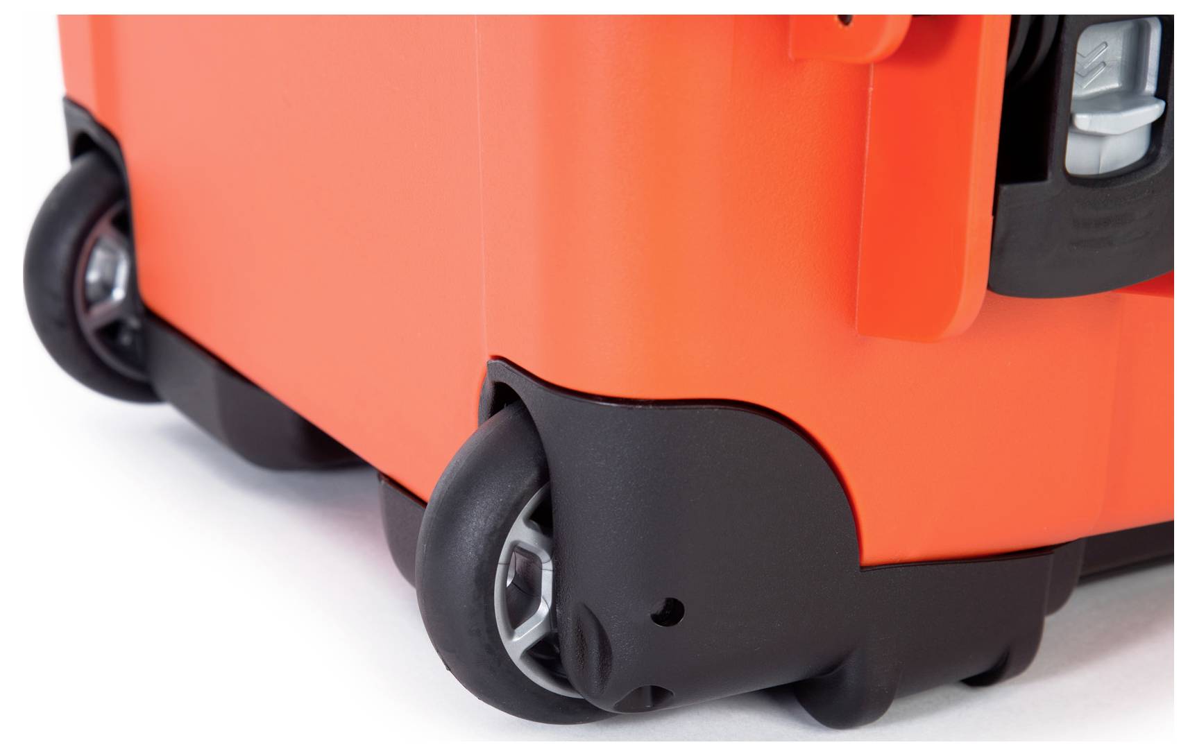 A brightly orange suitcase with sturdy black wheels on a light surface; focus on the wheels for mobility.