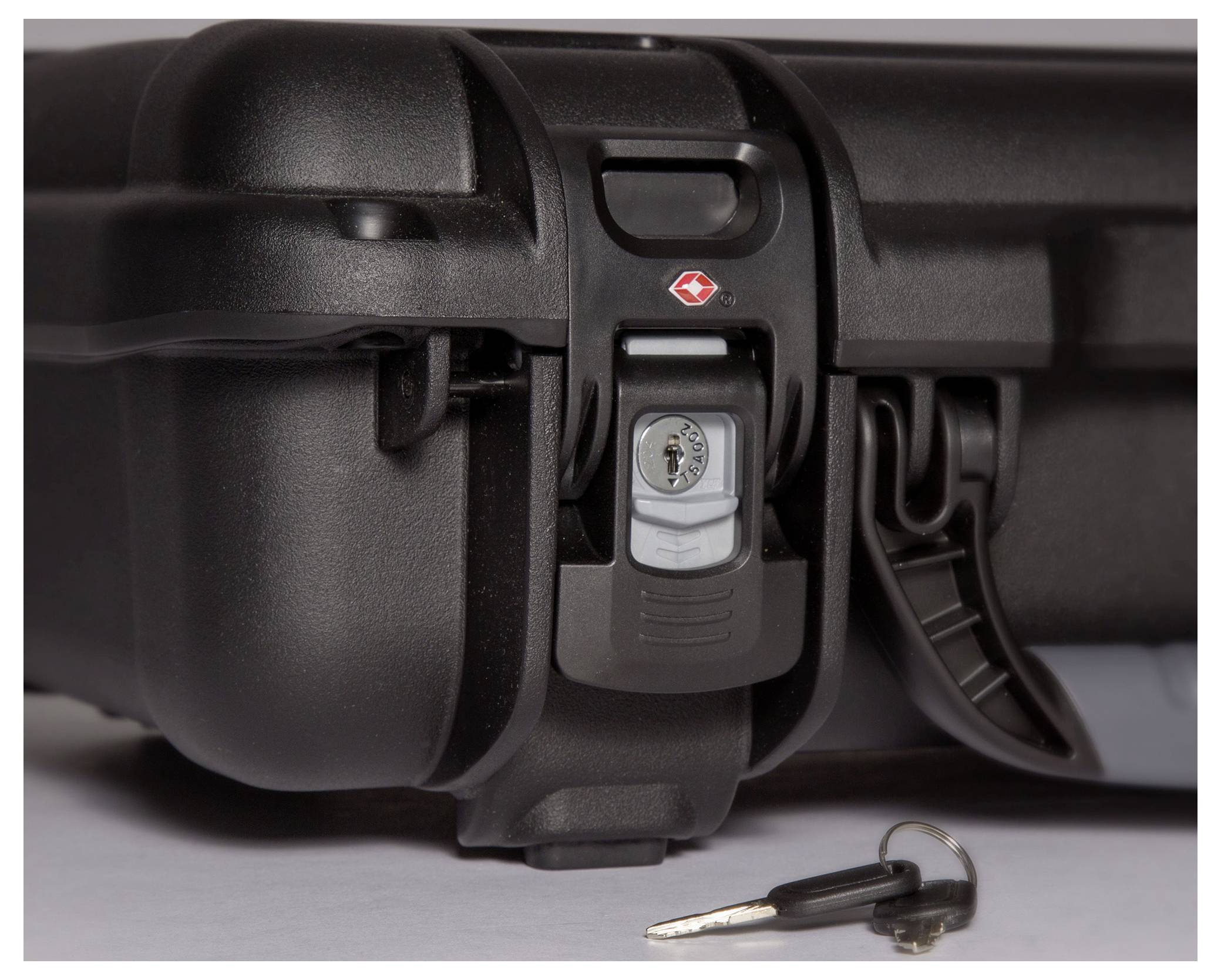 Black, locked suitcase with TSA lock and key beside it on a white background.