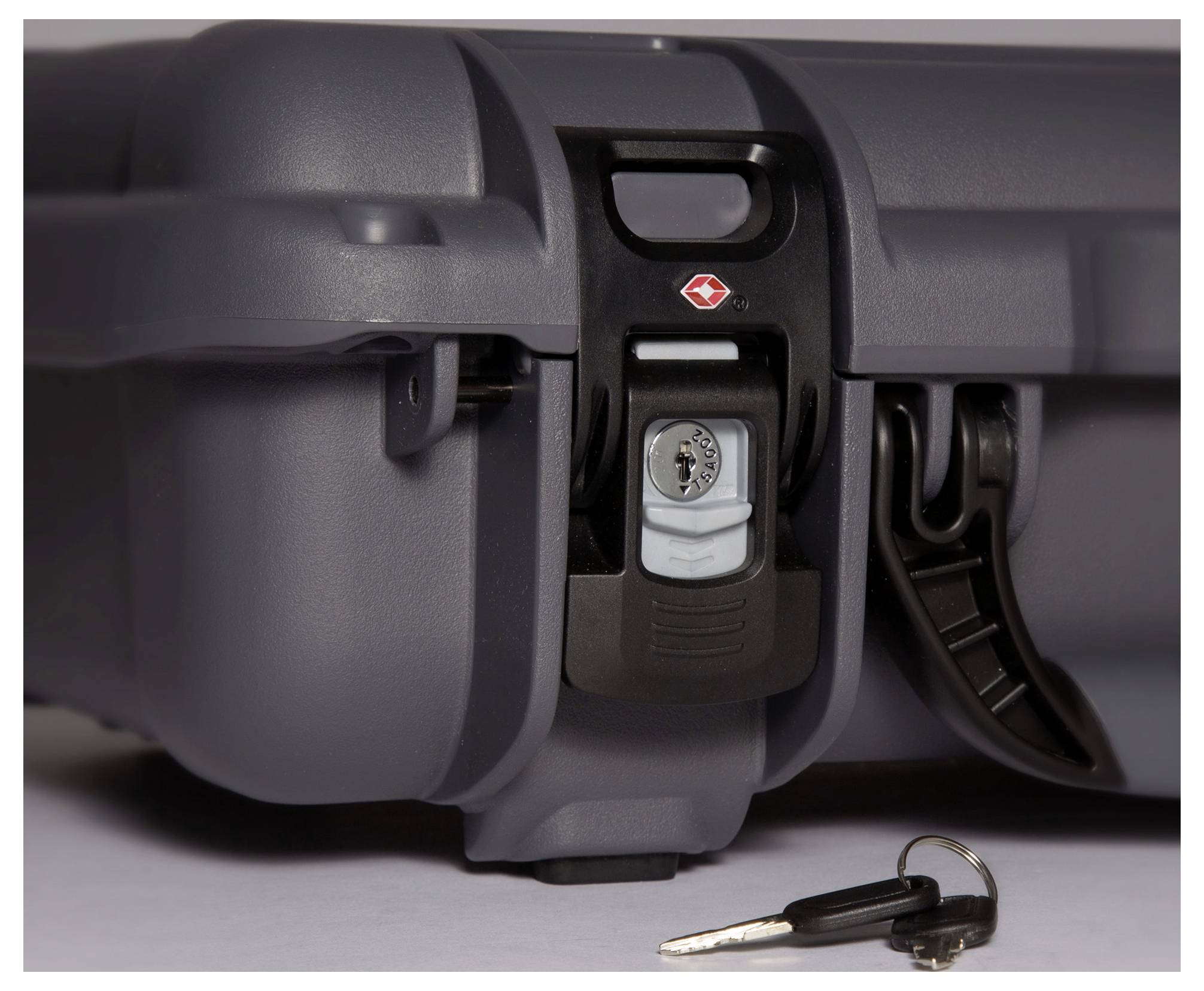 Close-up of a grey hard-shell suitcase with a closed combination lock. A key is positioned beside it.