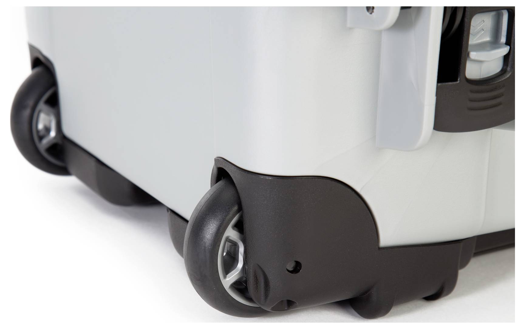 Close-up of black wheels at the corner of a grey suitcase. They are sturdy and designed for easy transportation.