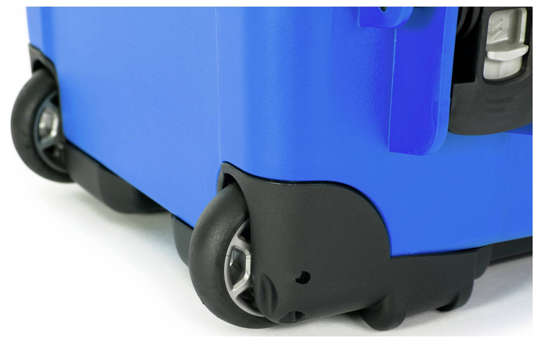 Blue suitcase with black wheels made of durable plastic. Right lower corner of the suitcase visible.