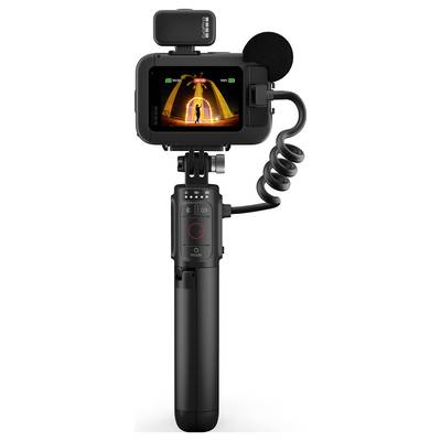 Digital camera with microphone and tripod, display shows person in front of illuminated gate.
