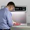 A man is examining an object under a light testing device used for checking colour consistency.