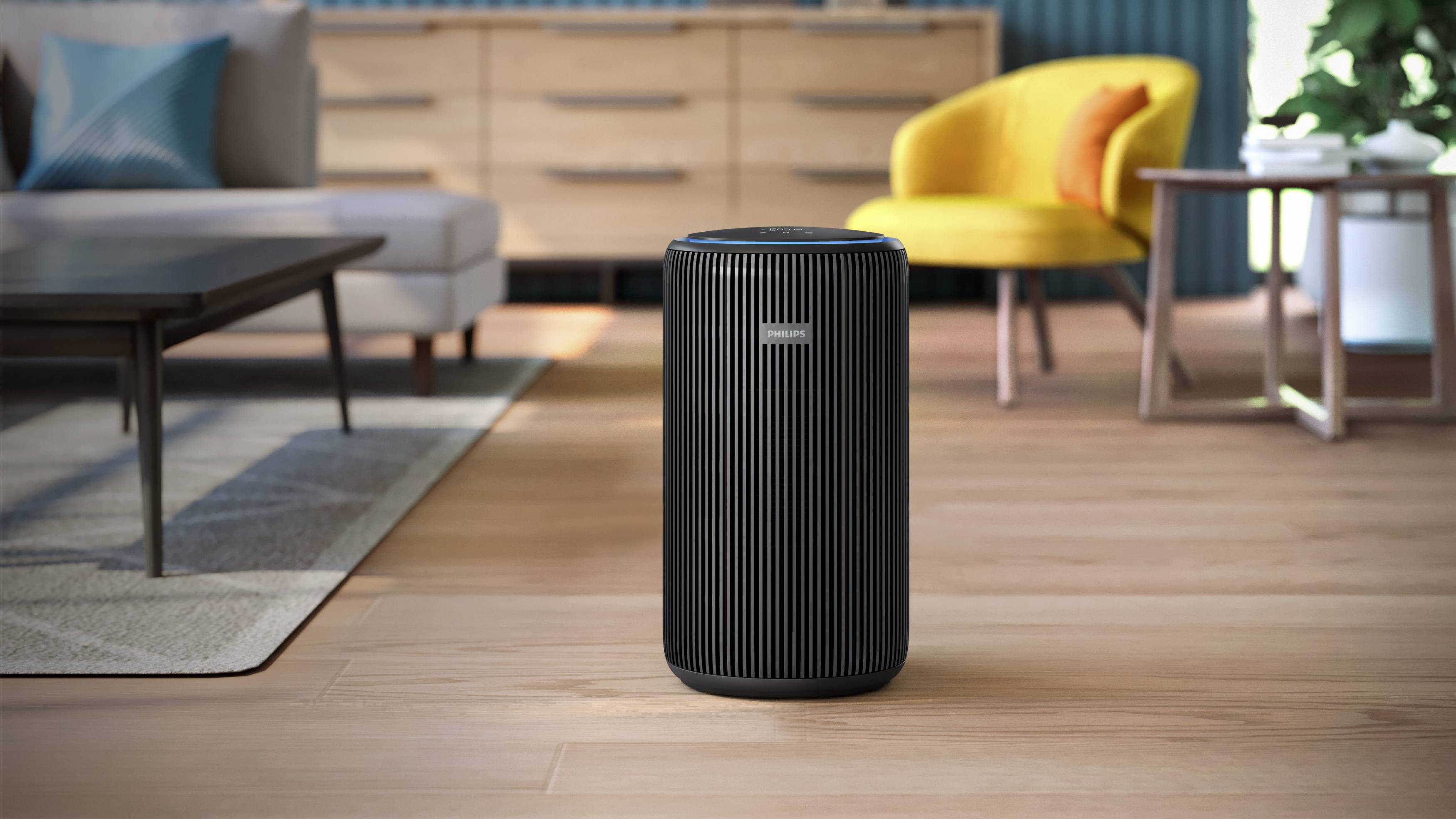A black air purifier stands on a wooden floor in a modern living room, surrounded by a sofa, a table, and a yellow chair.