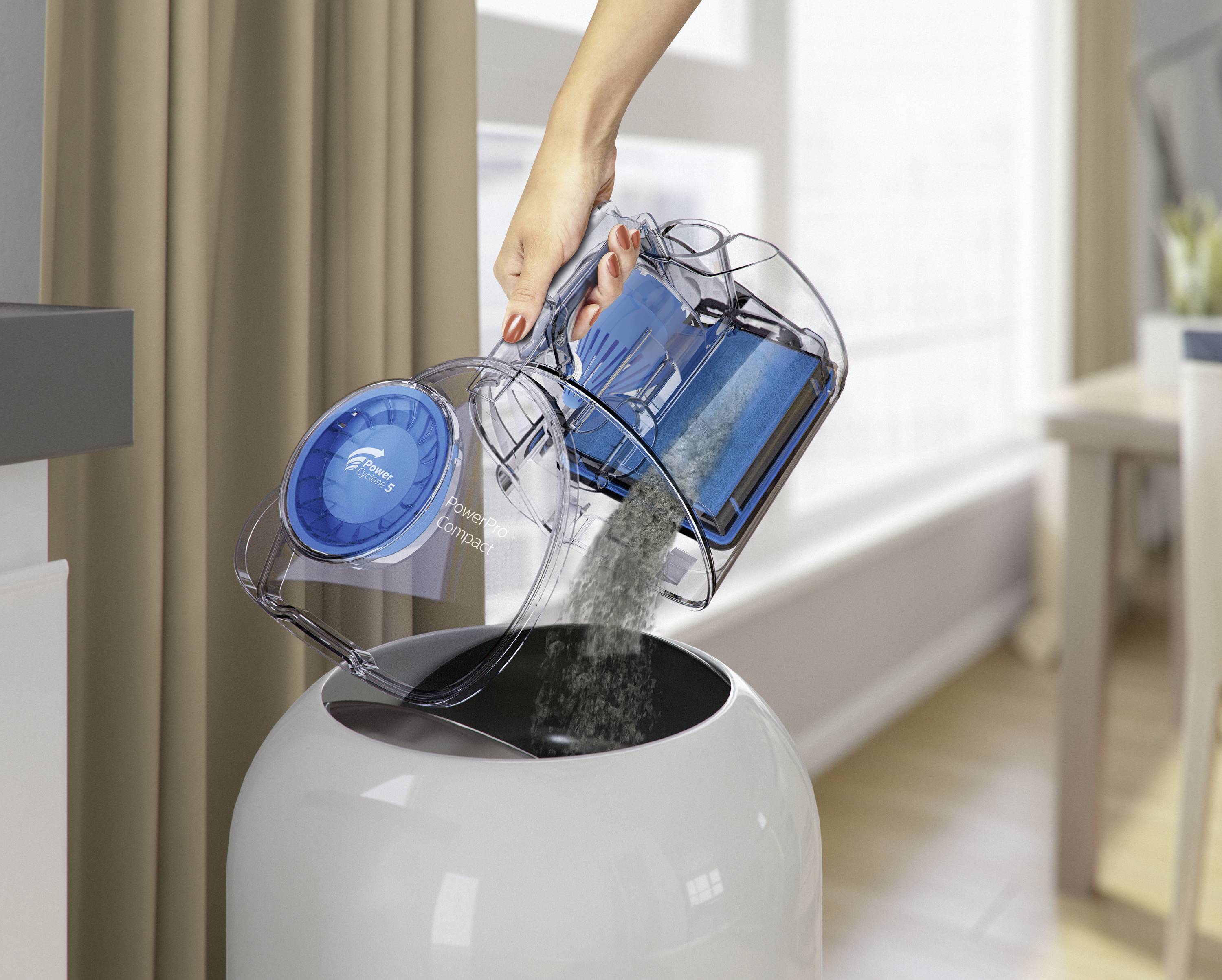 A person empties the dust container of a vacuum cleaner into a rubbish bin in a bright, modern room.