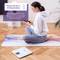 A woman sits on a yoga mat and looks at her smartphone. Weighing scales nearby. Text field: 'Measure up to 19 body indices'.