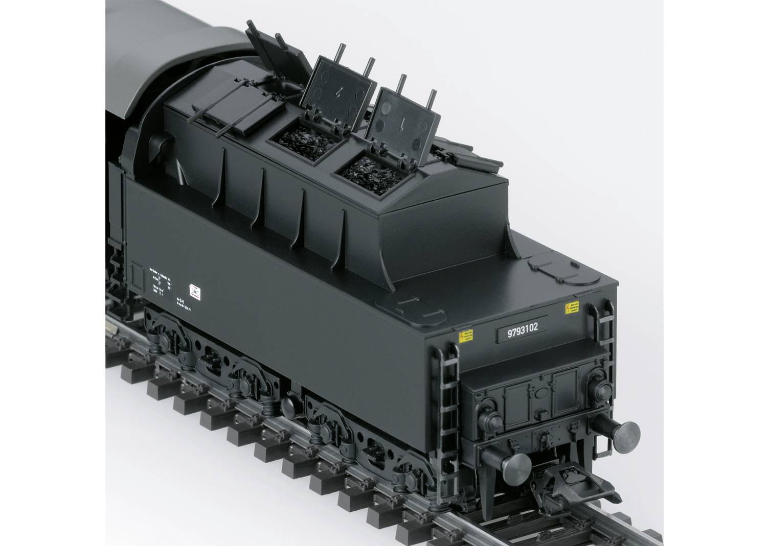 The image depicts a black model of a railway tender with detailed structures and markings on the tracks.