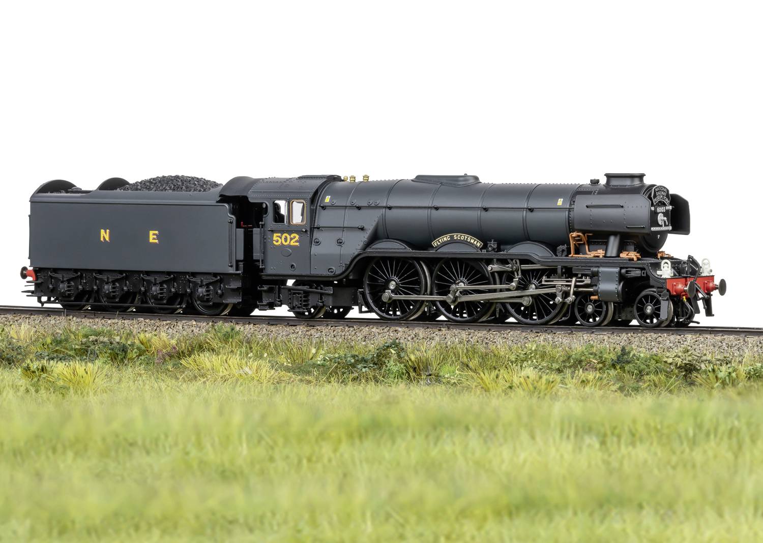 Black steam locomotive on railway tracks, side view, surrounded by grassland. Locomotive number '502' clearly visible.