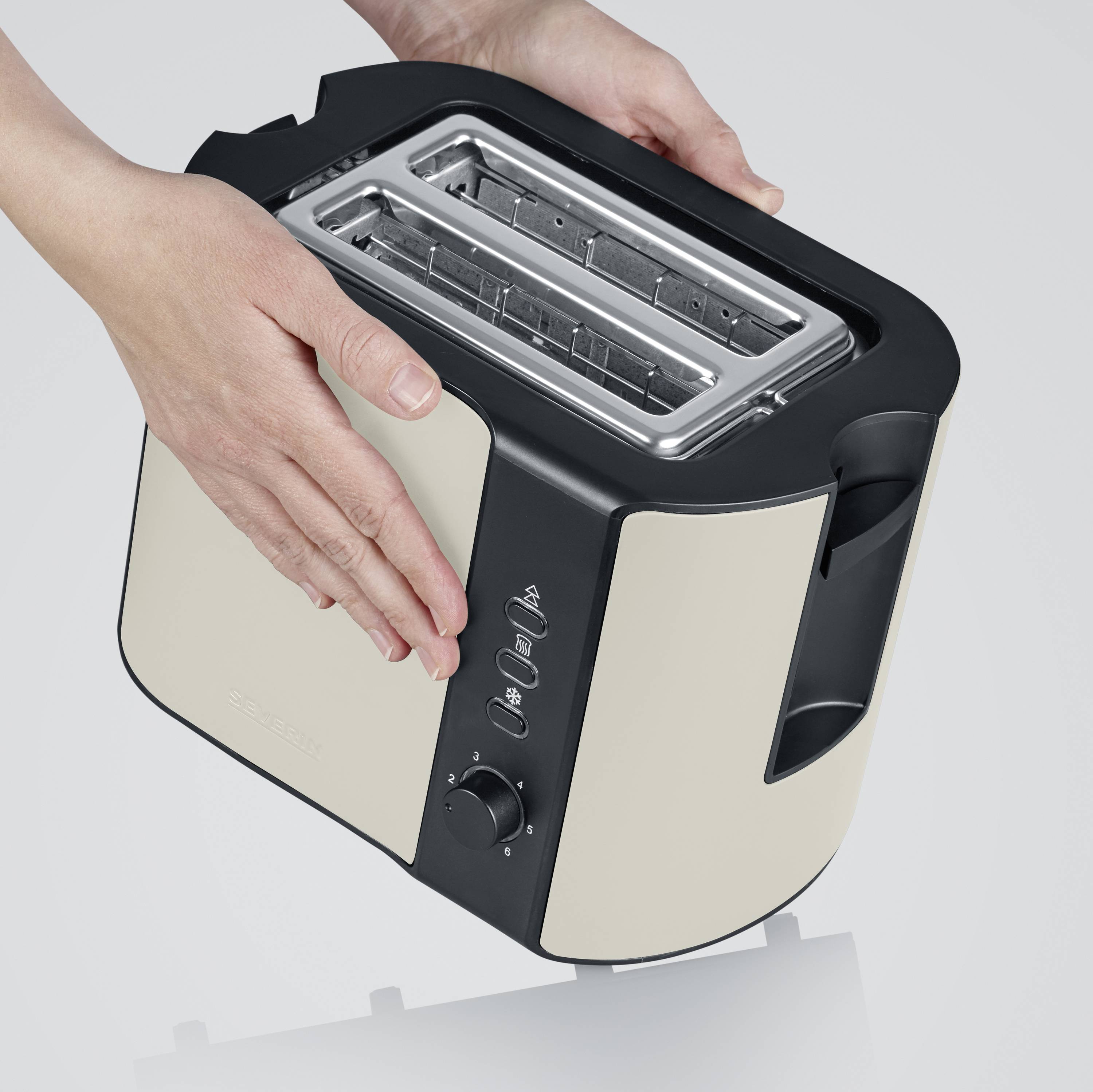 A silver and black two-slice toaster is being held by a hand. Control buttons are visible at the front.