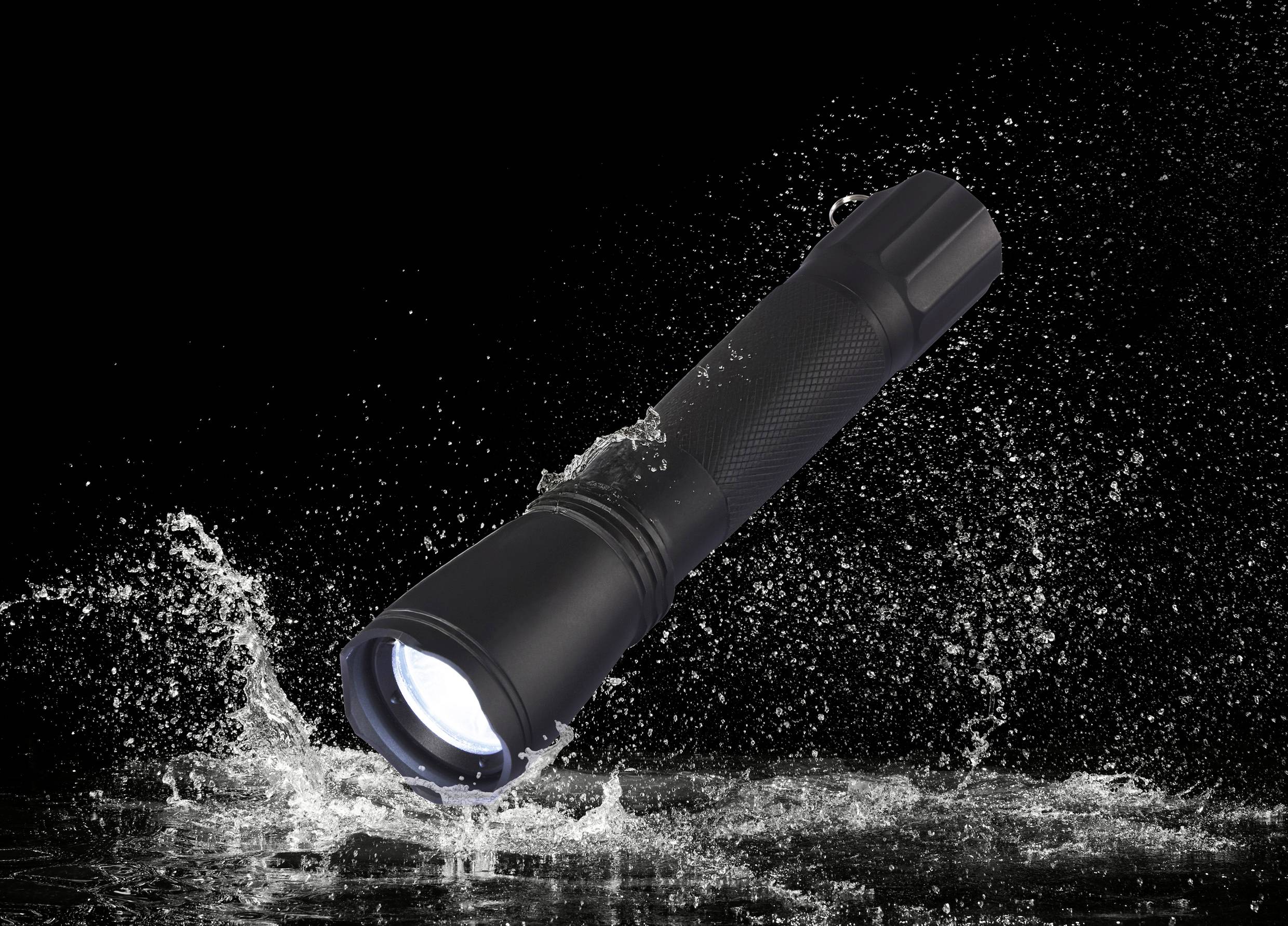 A black torch shines brightly and splashes water on a dark surface.