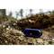 Portable Bluetooth speaker placed on a tree trunk outdoors, surrounded by blurred natural scenery.