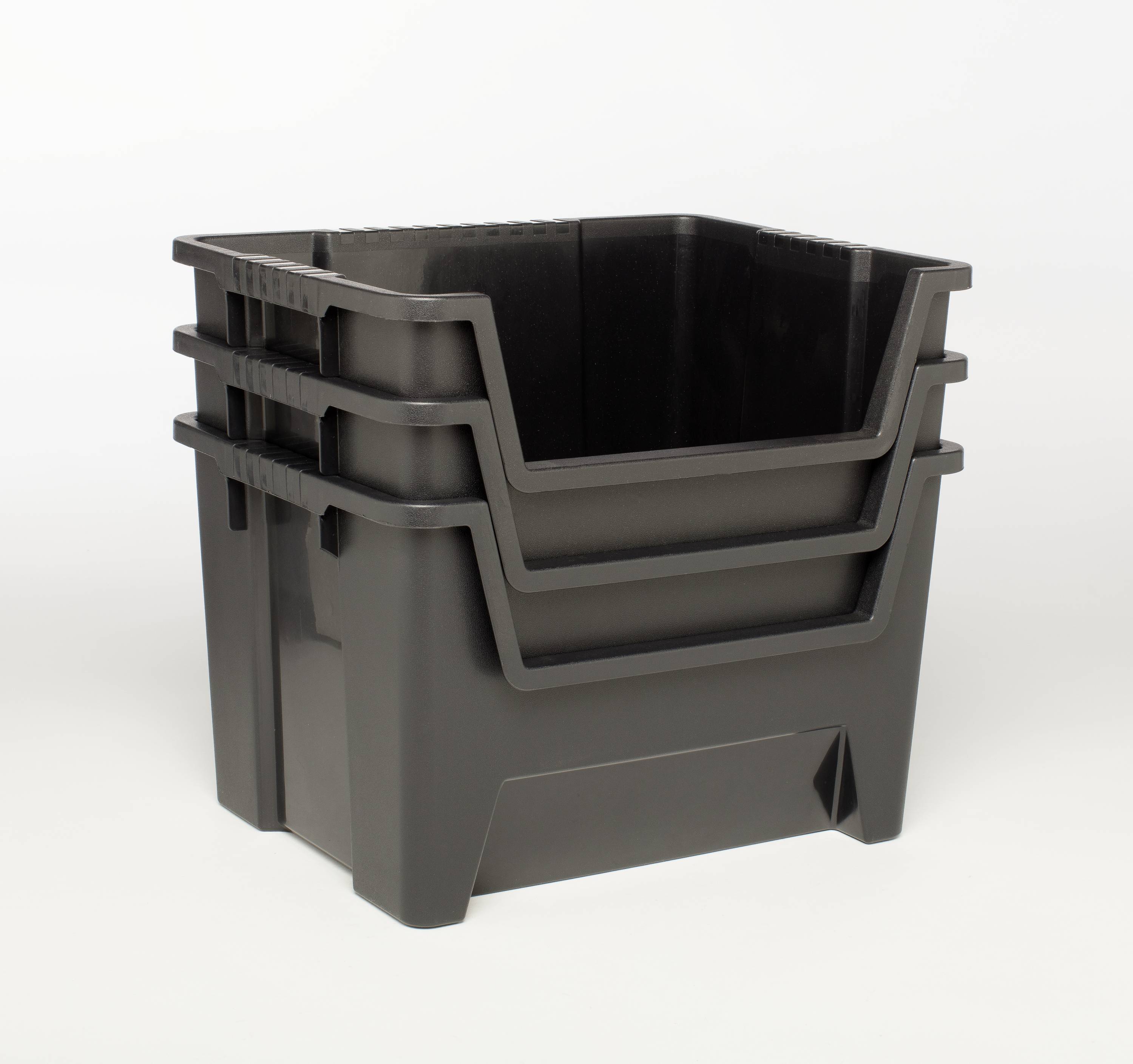Three black plastic crates stacked inside one another in front of a white background.