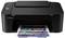 Black multifunction printer on a table, printing a document with images and text.
