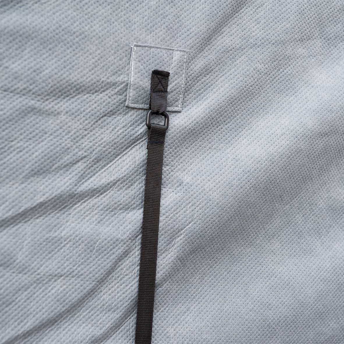Grey textile surface with a black, secured strap loop attached to a square seam.