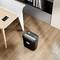 An office with a desk, on which a mobile phone rests. Beside it, a paper shredder and a bookshelf. Wooden flooring in the background.