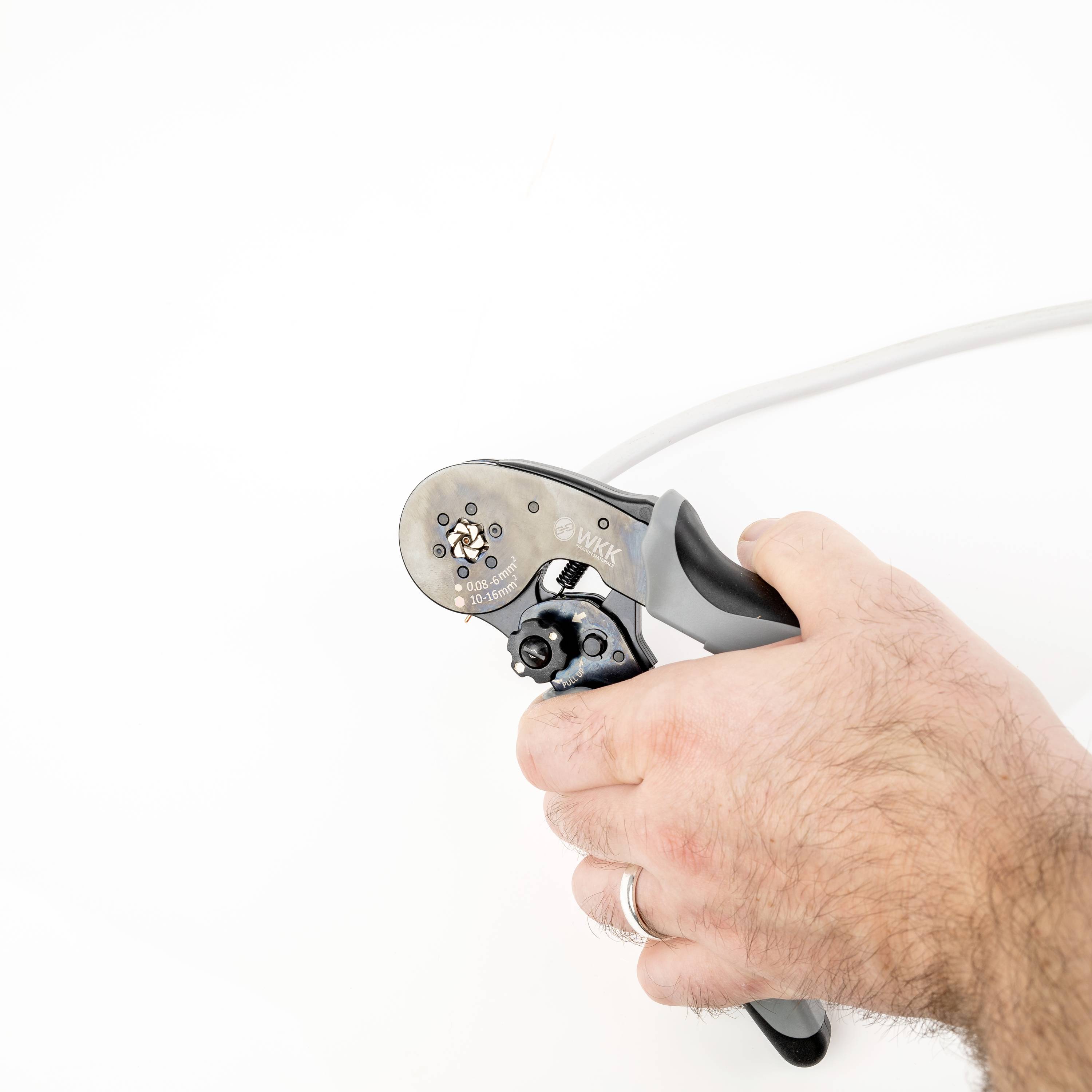 A hand is holding a crimping pliers used to securely fasten cable connections. The pliers are black and silver.