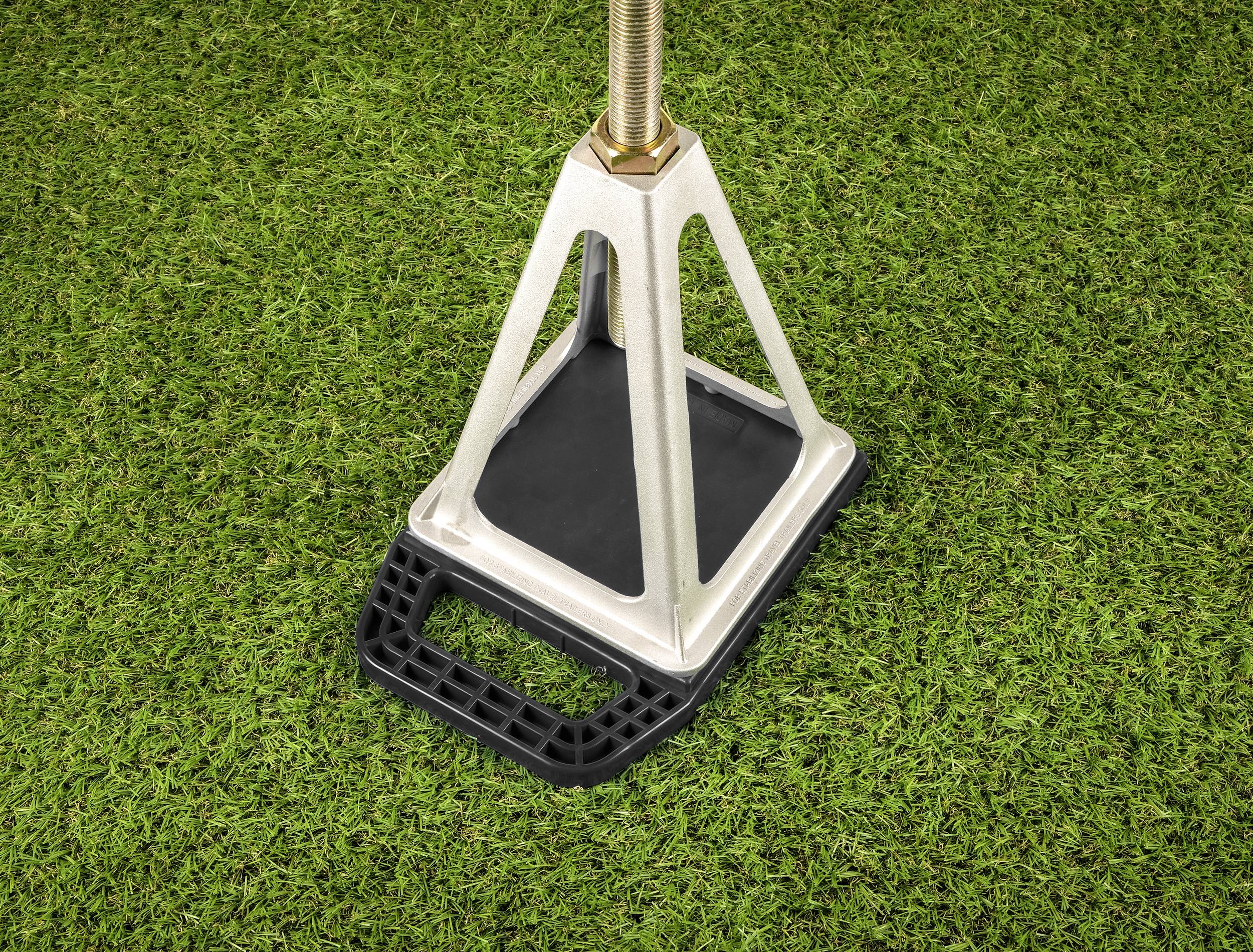 A metallic structural element on a lawn area, stabilised by a black, rectangular base with a handle.