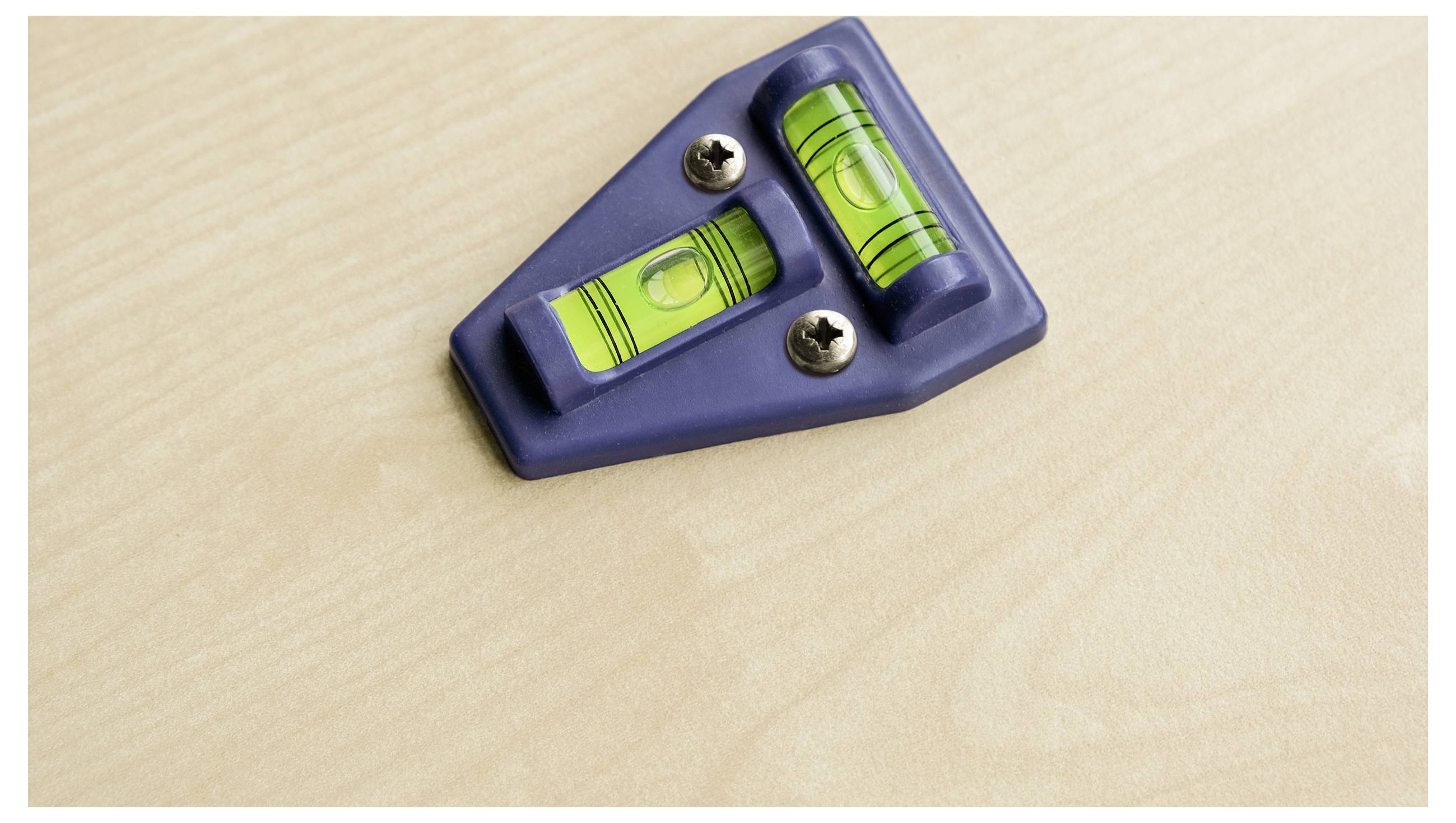 Spirit level with two vials resting on a wooden table.