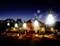 String of illuminated light bulbs at night, with blurred tents and lanterns in the background creating a cosy atmosphere.