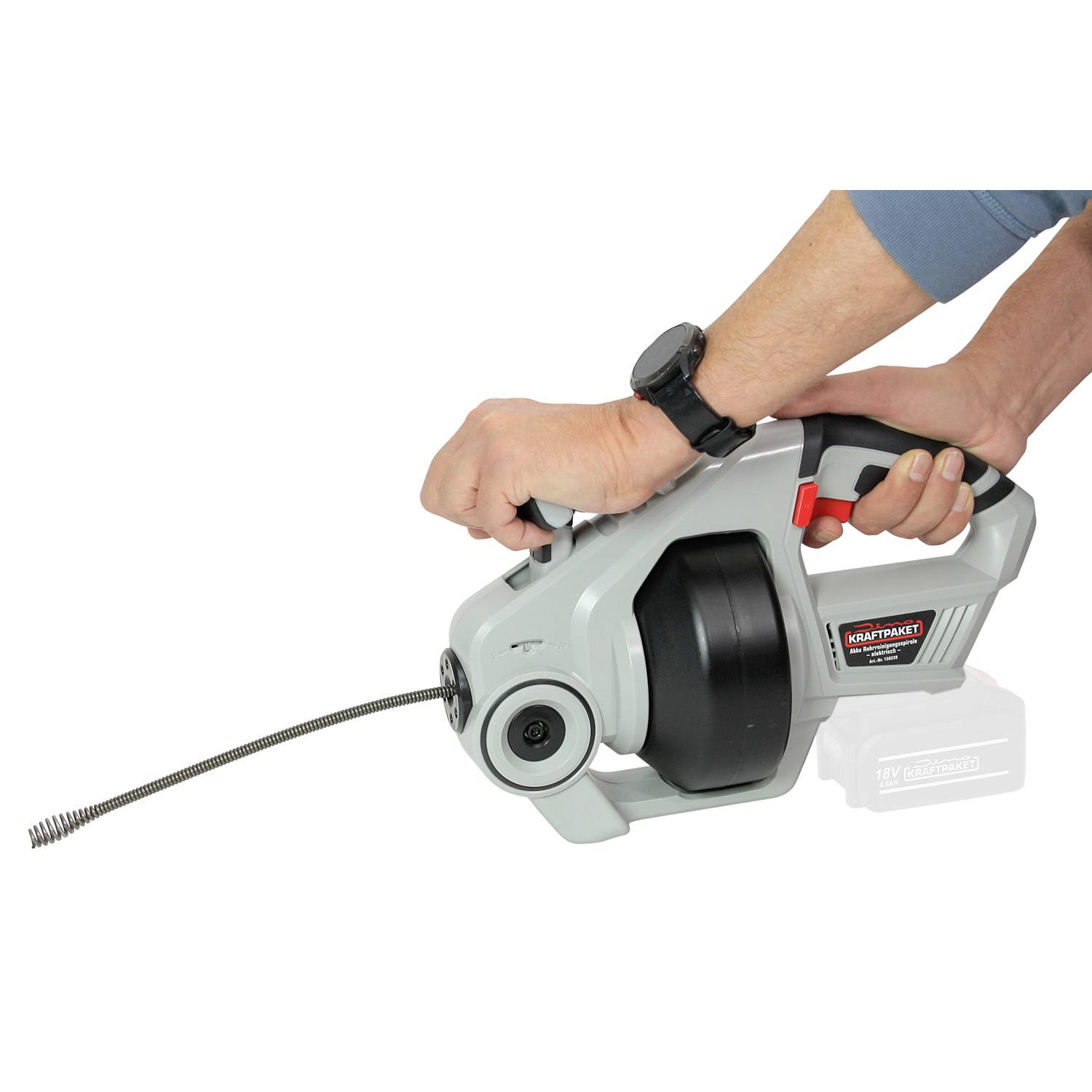 A person is operating a portable drain rodding machine with a flexible cable to clear blocked pipes.