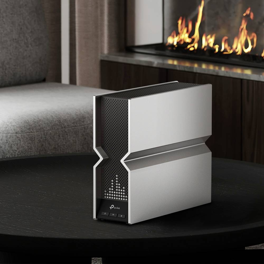 Small, modern air purifier on a table in a living room, next to a lit fireplace. Subtle, geometric design.