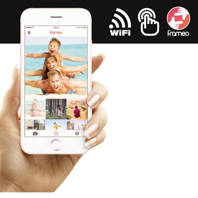 A hand is holding a smartphone with a photo of children laughing on the beach displayed on the screen. Symbols for 'WiFi' and 'frameo' are located at the top.