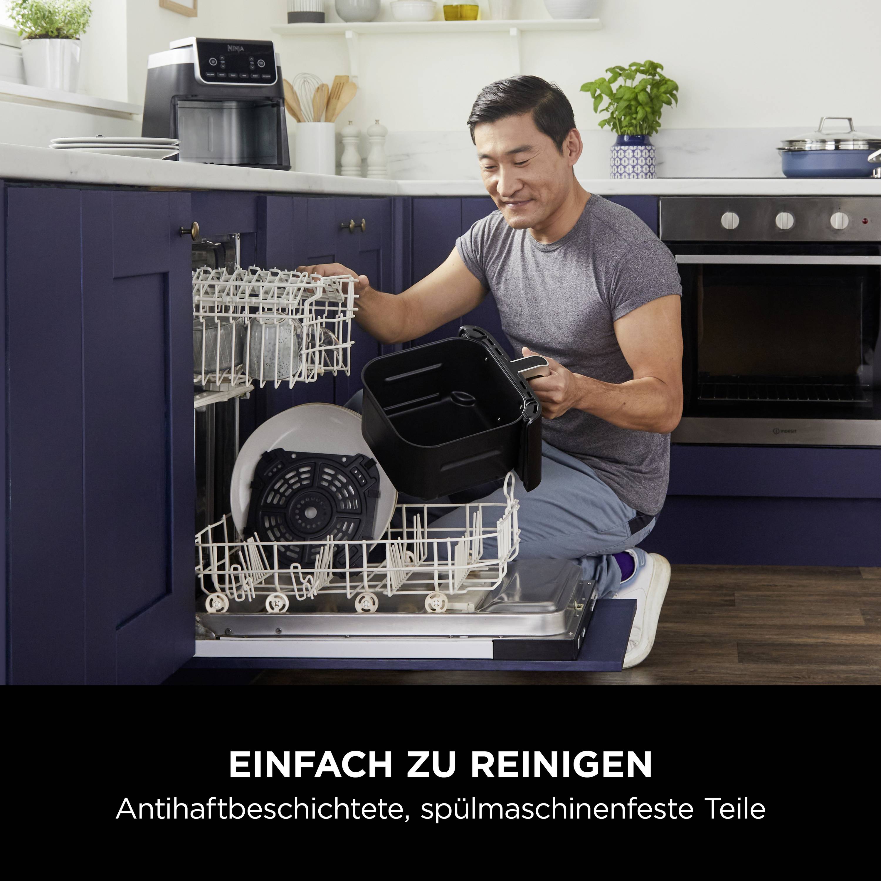 A man is loading the dishwasher with black kitchen utensils. Text below reads: 'Easy to clean. Non-stick coated, dishwasher-safe parts'.