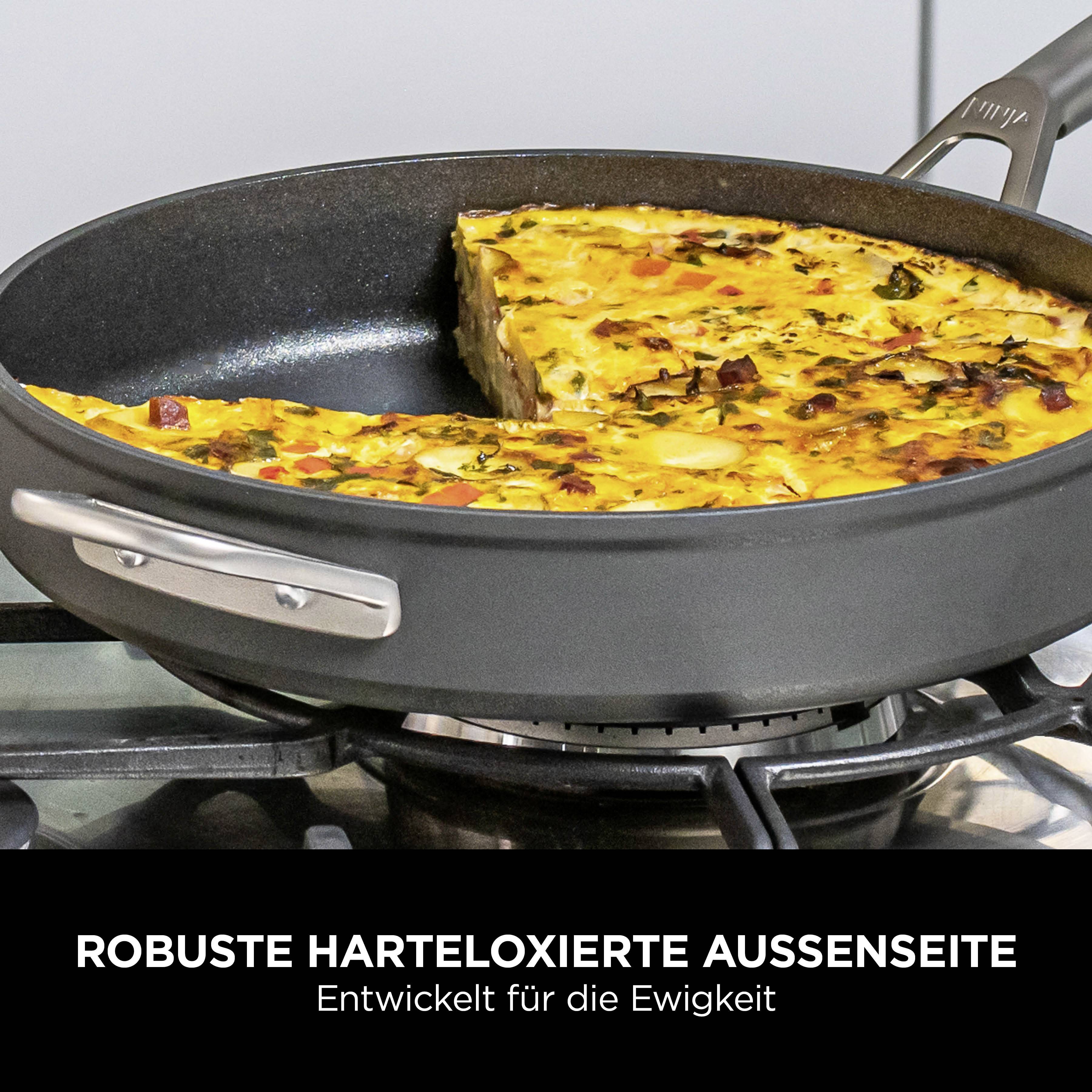 A black pan contains a piece of vegetable quiche. The text describes the pan as having a 'robust hard-anodised exterior'.
