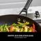 A pan with colourful vegetables on a hob. The handle bears the inscription 'Ninja'. Text describes the stainless steel handle.