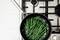 A black pan with green beans on a hob. The beans are evenly distributed and partially browned.