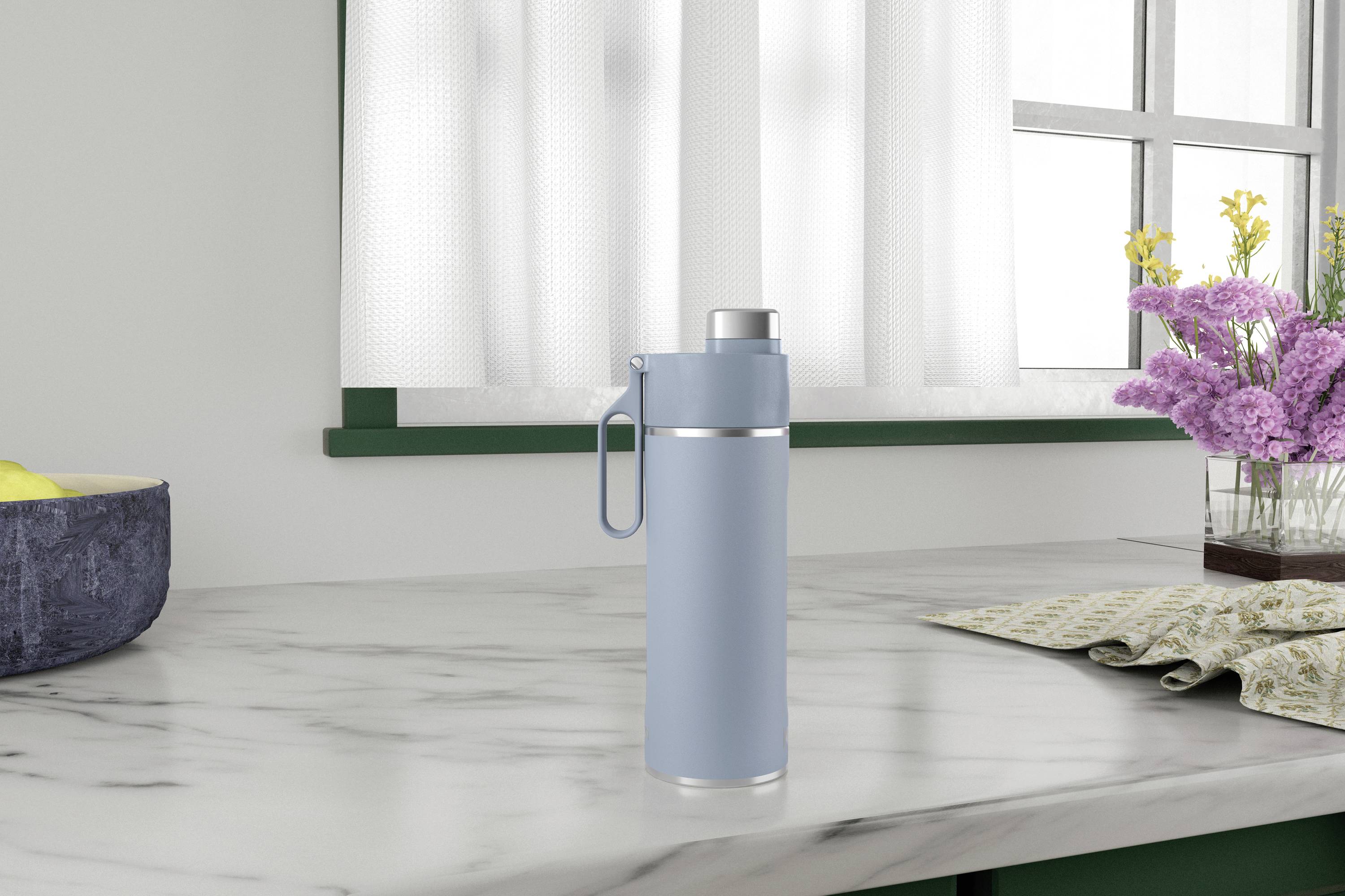 A light blue thermos flask is sitting on a marble worktop in a kitchen next to a flower vase and a bread basket.