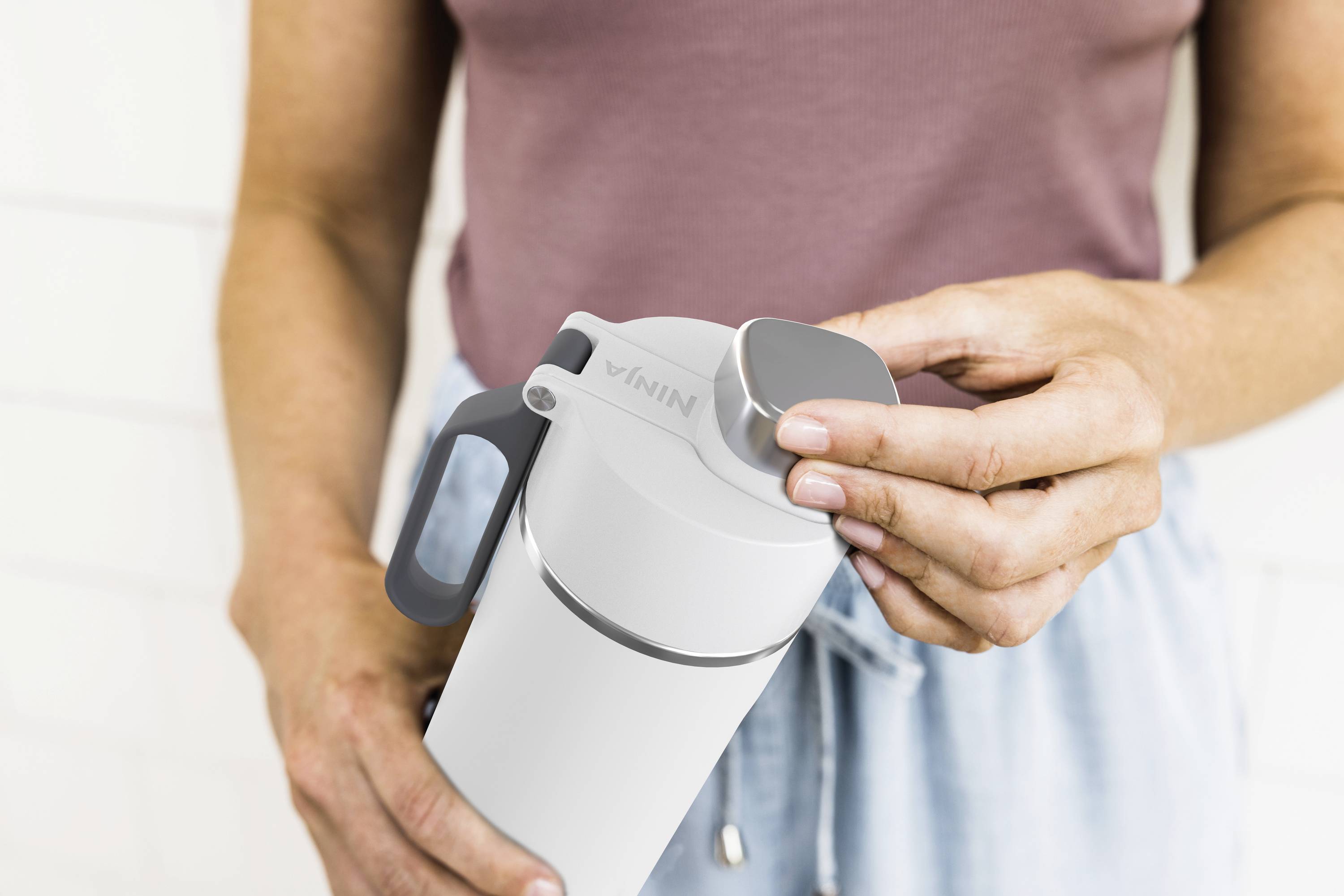 A person is holding a white drinking bottle and opening the cap.