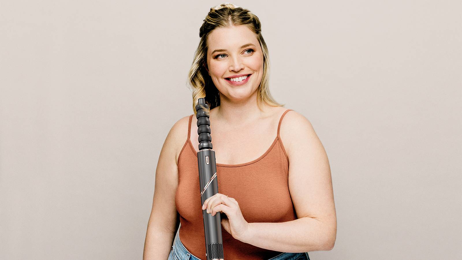Woman in a sleeveless top, smiling, holding a vacuum cleaner.