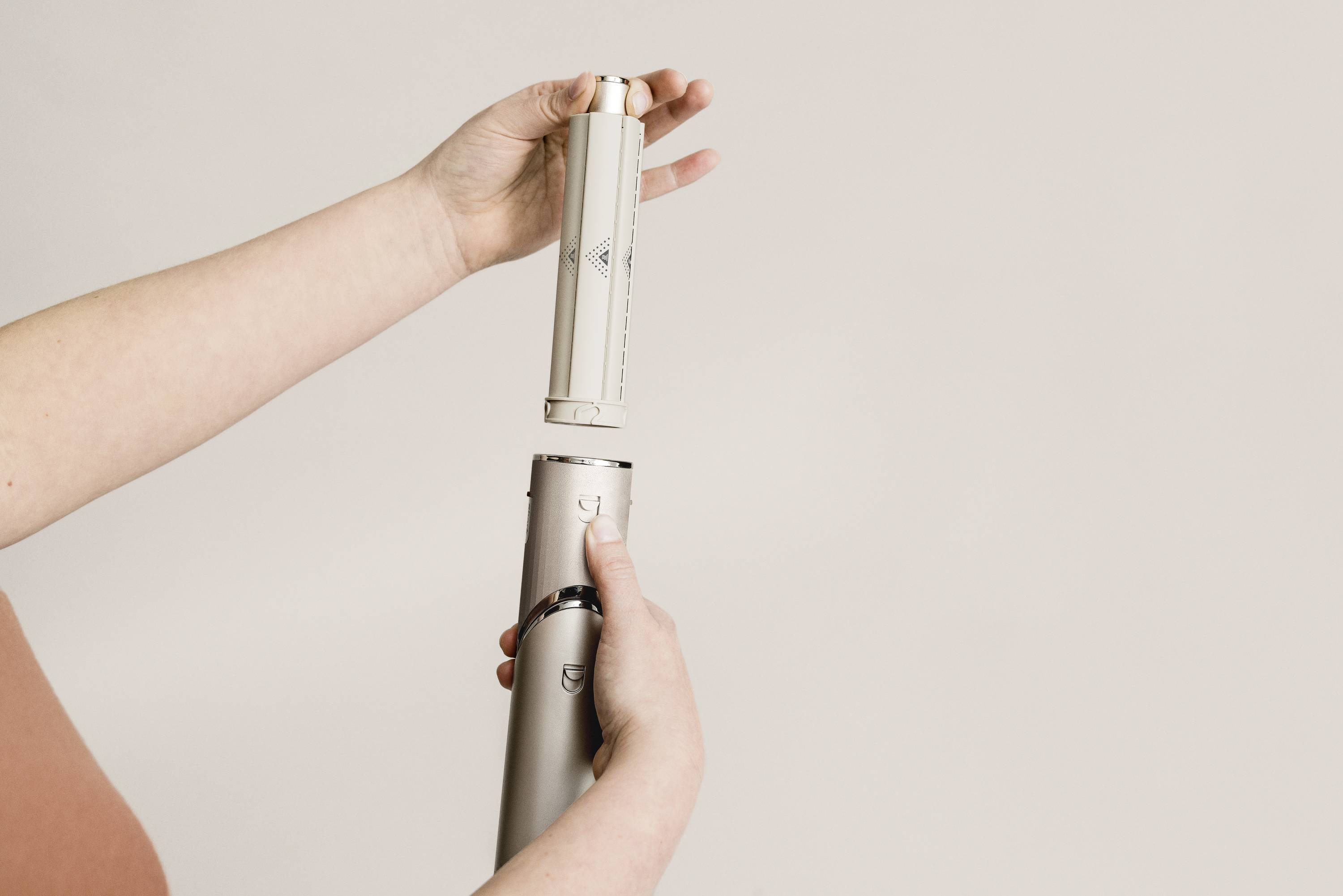 A person is holding two tubular parts that are to be connected. Hands are demonstrating the assembly of an unknown device.