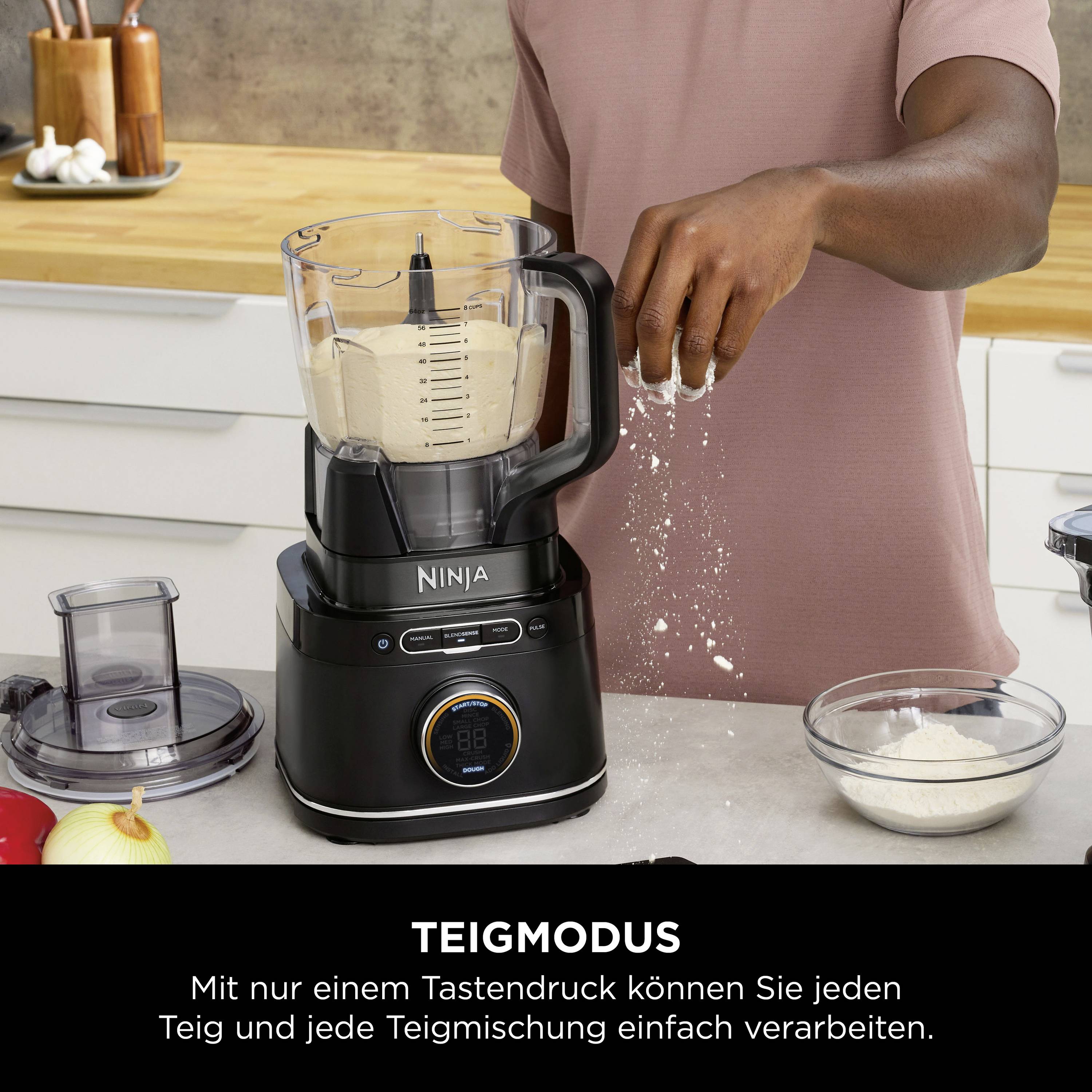 A person is using a mixer to prepare dough. The display reads 'Dough Mode'. A worktop with ingredients is in the background.