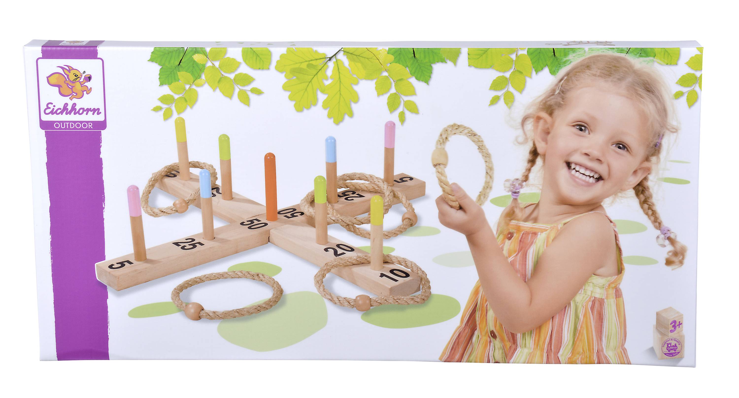 A laughing child plays with a wooden ring toss game. The set includes wooden sticks and rings, which are placed on a green lawn.
