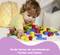 A child is playing with colourful building blocks on a table. Text underneath: 'Children learn about different shapes and colours.'